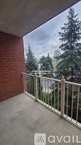 A balcony with a metal railing and a view of trees.