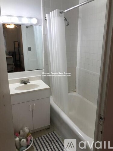 A white bathroom with a sink, mirror, and shower.