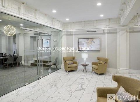 A spacious room with a glass wall and a chandelier.