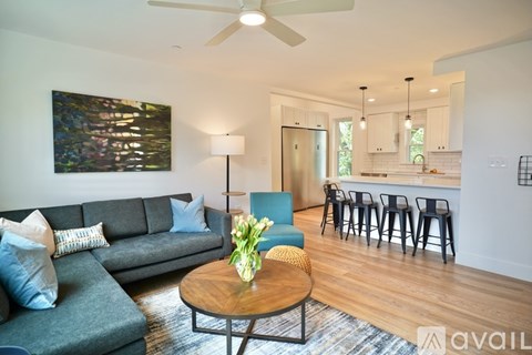 A living room with a grey couch, a wooden coffee table, and a painting on the wall.