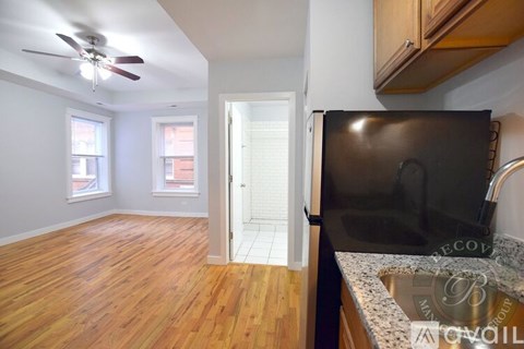 A kitchen with a black fridge and wooden floors.
