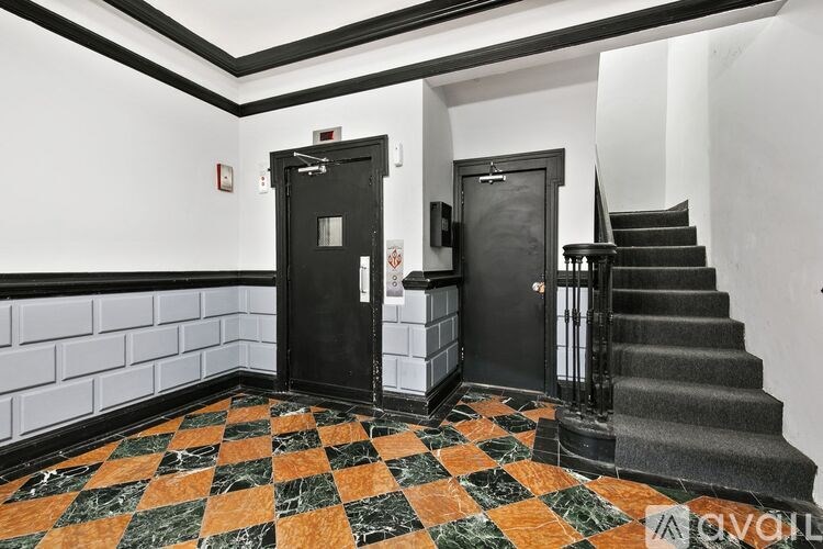 A hallway with a black and white checkered floor and a staircase.