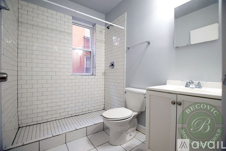 A white toilet sits in a bathroom with a white sink and a white cabinet.