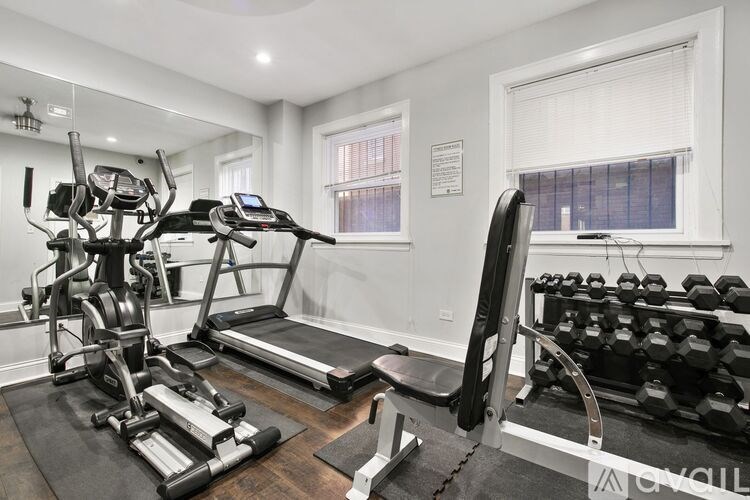 A well-equipped home gym with a treadmill, stationary bike, and dumbbells.
