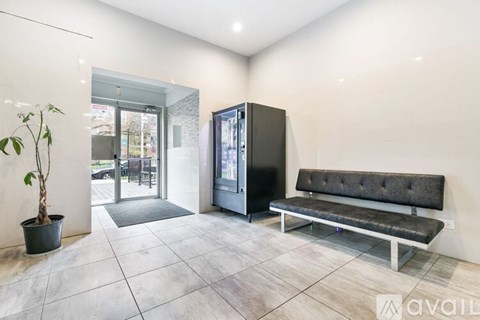 A room with a bench, a plant, and a fridge.