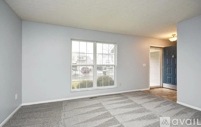 A room with a carpeted floor, a window, and a door.