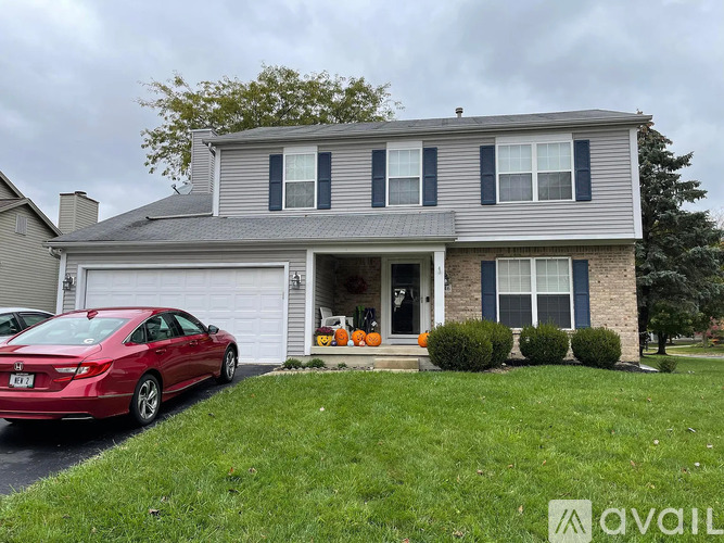 A red car is parked in front of a house with a garage.