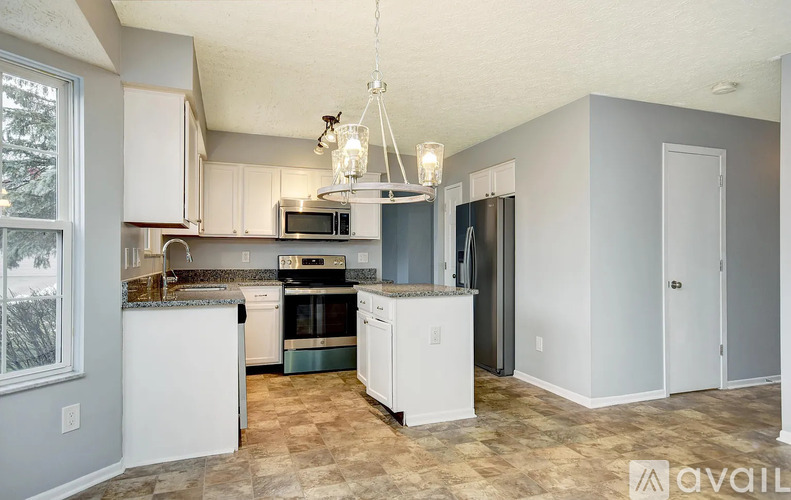 A kitchen with white cabinets and appliances, a checkered floor, and a chandelier hanging from the ceiling.