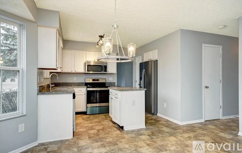 A kitchen with white cabinets and appliances, a checkered floor, and a chandelier hanging from the ceiling.