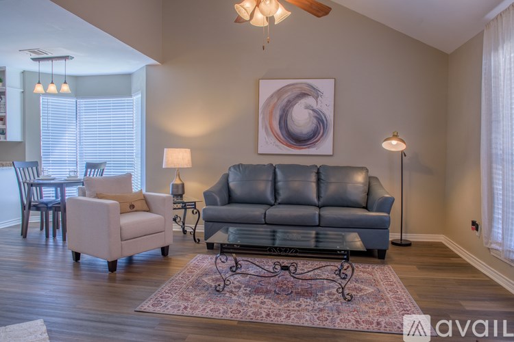 A living room with a grey couch, a white chair, and a rug.