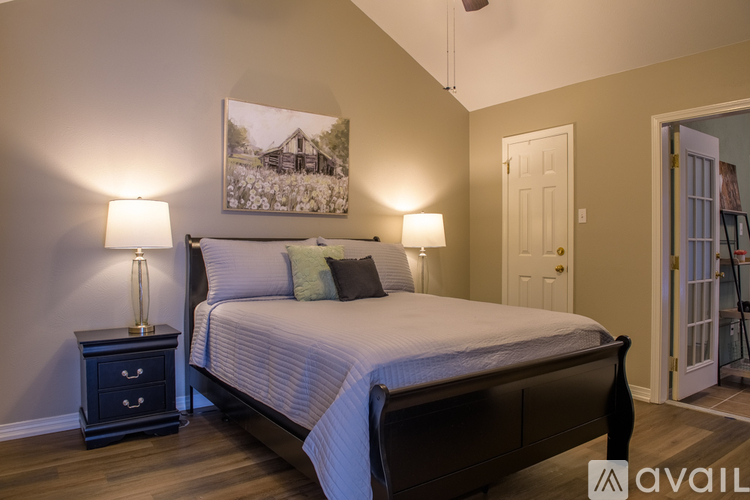 A bedroom with a bed, nightstand, and a painting on the wall.