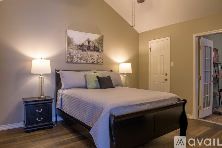 A bedroom with a bed, nightstand, and a painting on the wall.