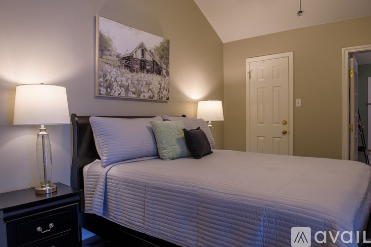 A bedroom with a bed, two lamps, and a painting on the wall.