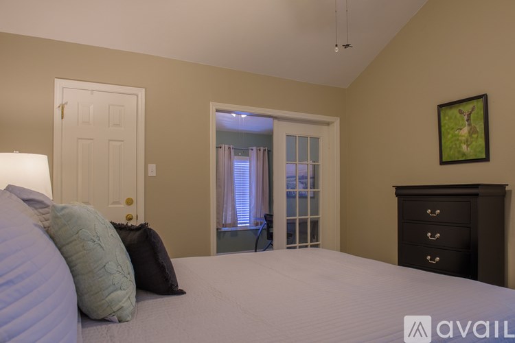 A bedroom with a large bed, a dresser, and a painting of a deer on the wall.