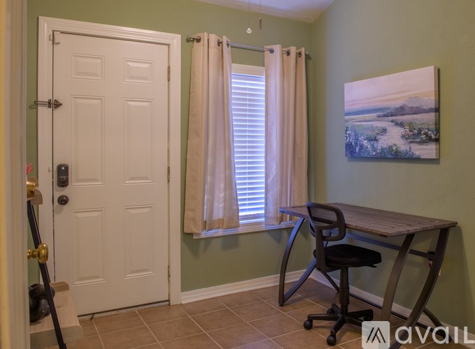 A room with a desk and chair in front of a window with curtains.
