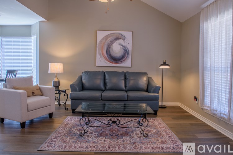 A living room with a grey sofa, a white armchair, and a glass coffee table.