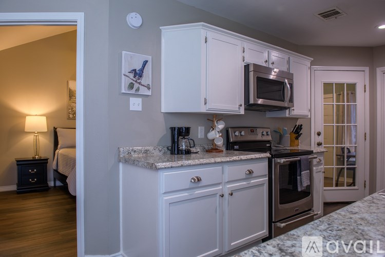 A kitchen with white cabinets and a marble countertop.