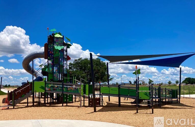 A playground with a green slide and a blue shade sail.