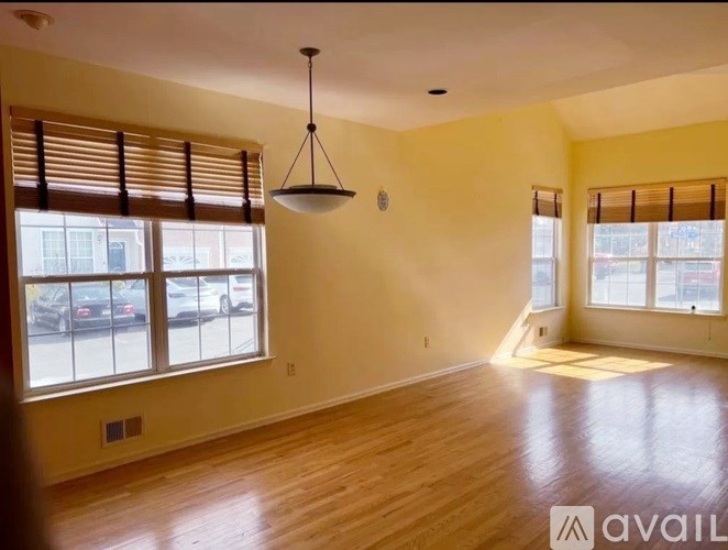 A room with wooden floors and a large window with blinds.