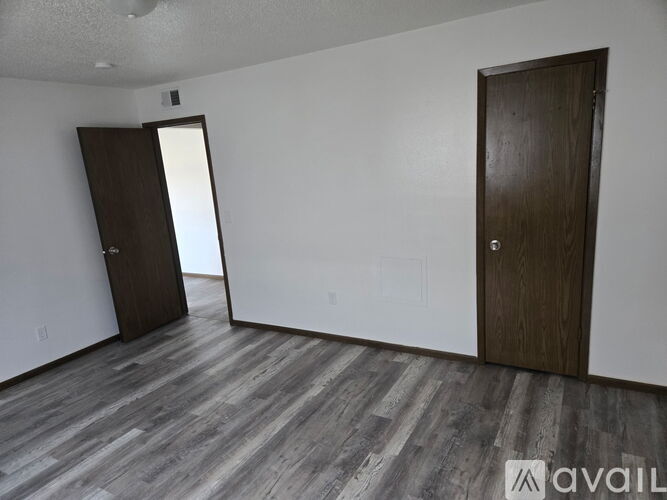 A room with wooden flooring and two doors.