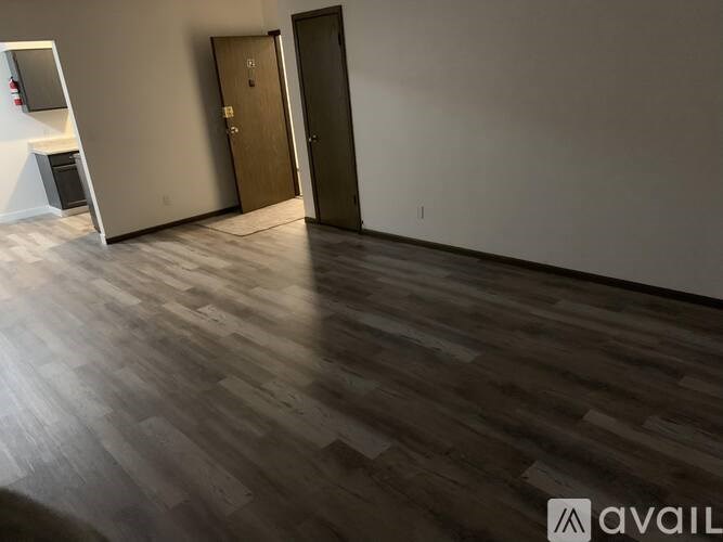 A room with wooden flooring and two doors.
