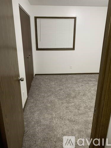 A room with a carpeted floor and a window with blinds.