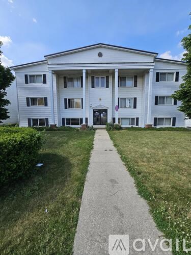 A white apartment building with a walkway in front.