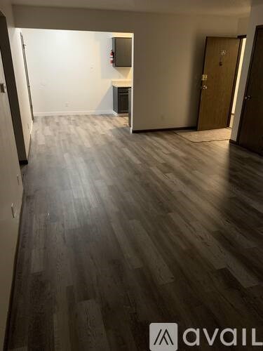 A room with wooden flooring and a door on the right side.