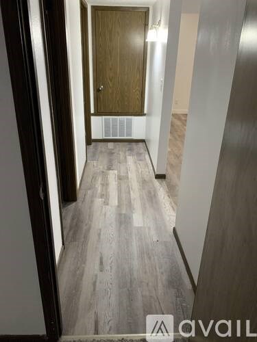 A hallway with a wooden door and a metal railing.