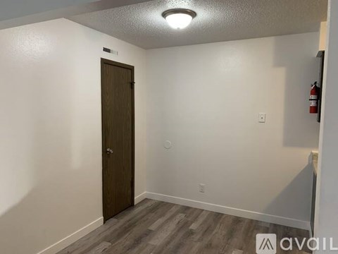 A room with a wooden door and a fire extinguisher on the wall.