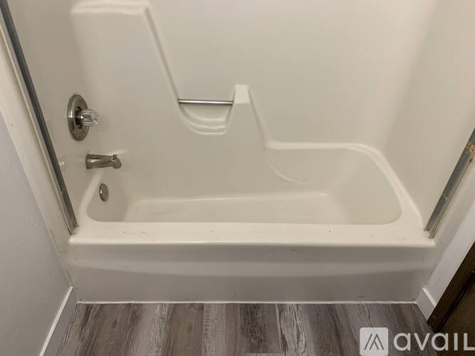 A white bathtub with a silver faucet and handle is installed in a bathroom.