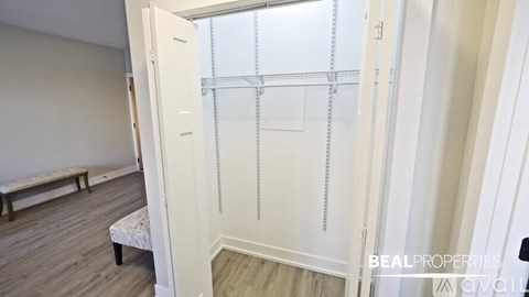 A white closet with a shelf and a bench in the corner of a room.