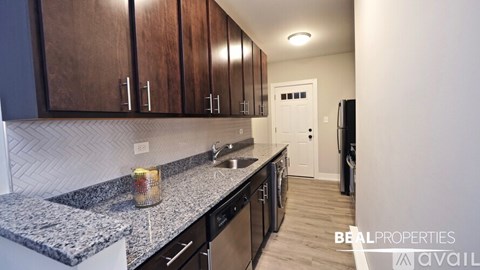 A kitchen with granite countertops and wooden cabinets is available for rent.