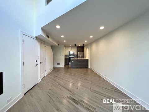 A spacious room with wooden flooring and a white door.