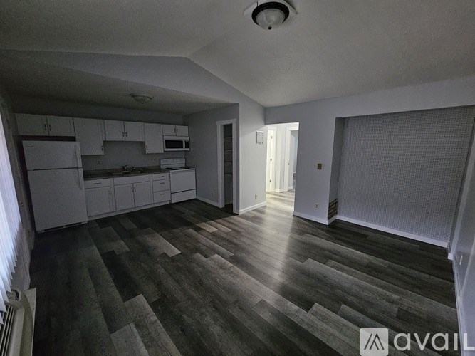 A spacious kitchen with white cabinets and a grey floor.