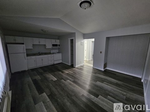 A spacious kitchen with white cabinets and a grey floor.