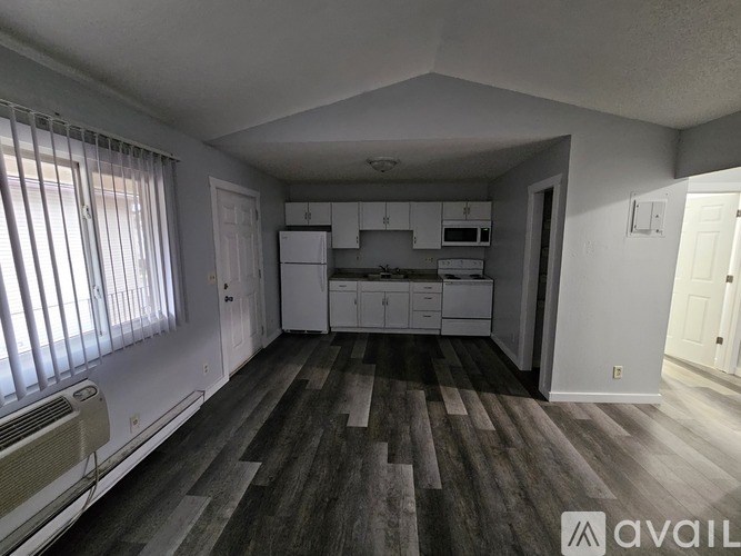 A spacious room with wooden flooring and white walls.