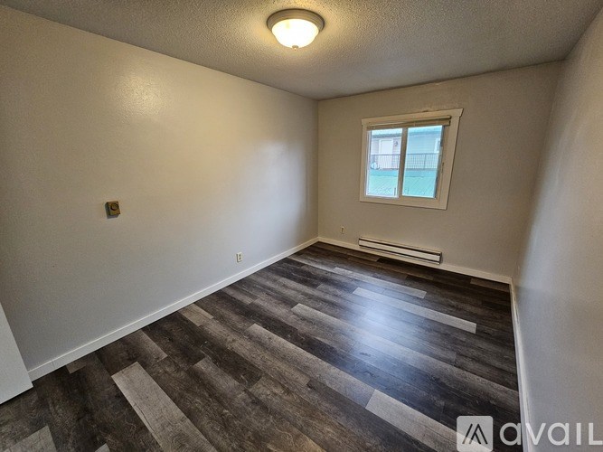 A room with a window and a wooden floor.
