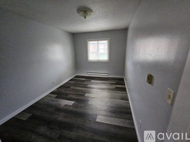 A room with a window and a wooden floor.