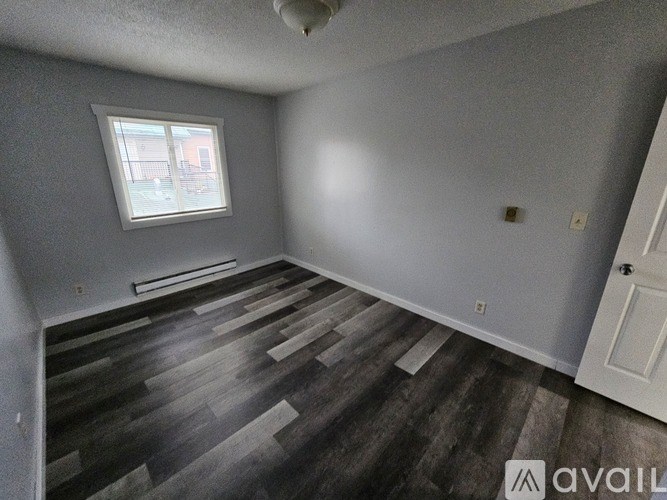 A room with a window and wooden flooring.