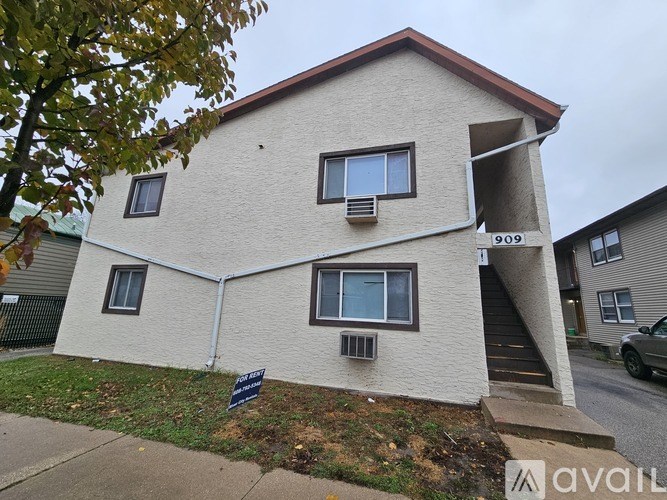 A two-story house with a white exterior and a red roof is numbered 909.