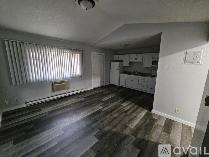 A room with wooden flooring and a window with blinds.