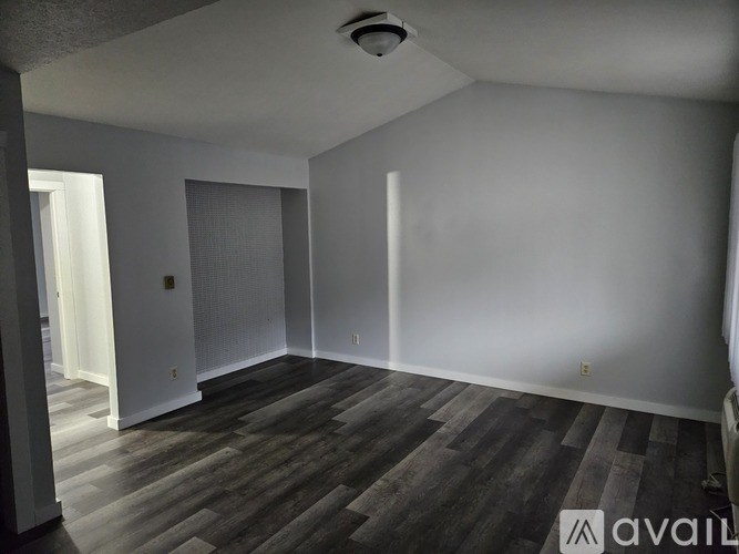 A room with wooden flooring and white walls.