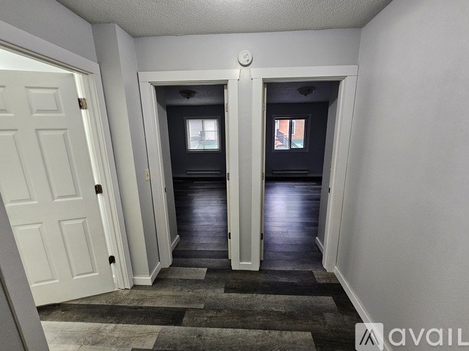 A hallway with two doors at the end and a carpeted floor.