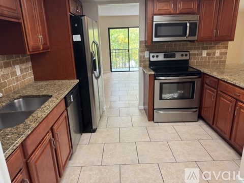 A kitchen with brown cabinets and a black refrigerator.