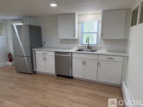 A kitchen with white cabinets and a wooden floor.