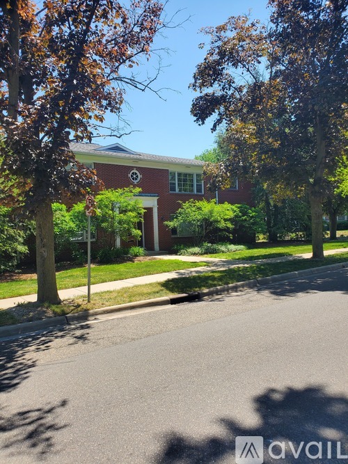 A tree with brown leaves stands in front of a red brick building.