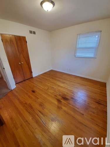 A room with wooden floors and a window with blinds.