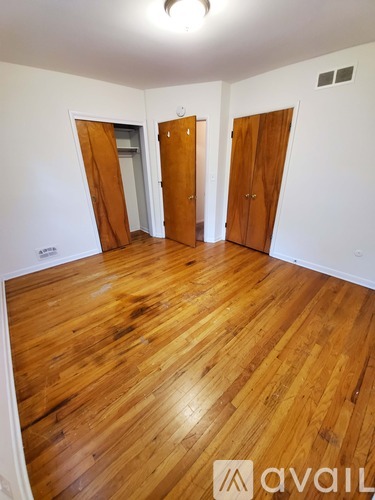 A room with wooden floors and three doors.