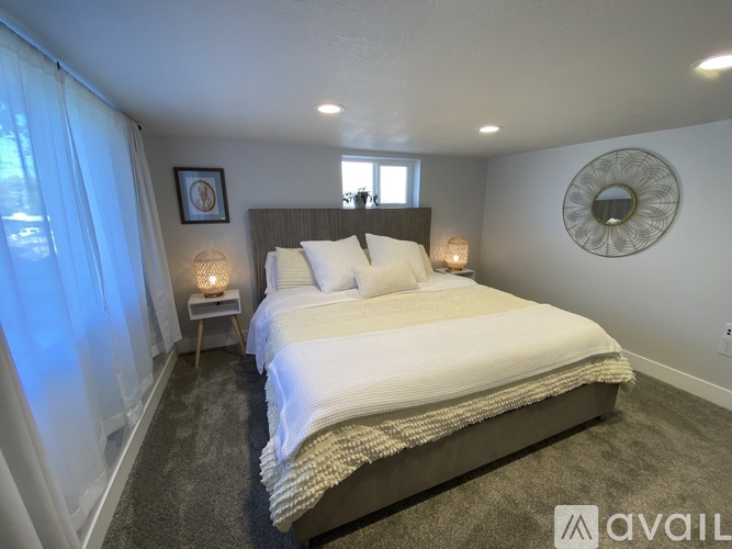 A bedroom with a large bed and a window with curtains.